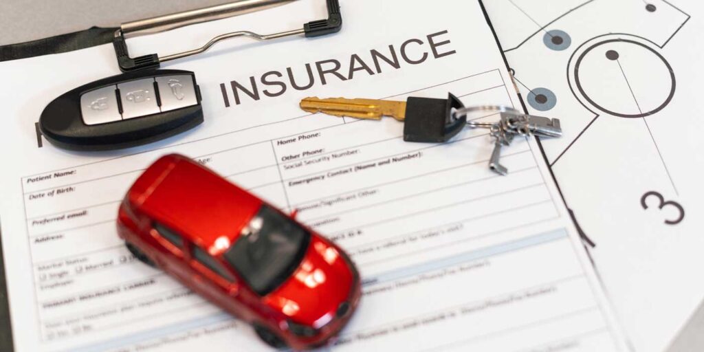 red toy car on top of car insurance paperwork